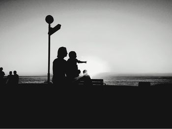 Silhouette people on beach against clear sky