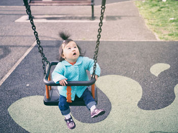 Boy sitting on swing at playground