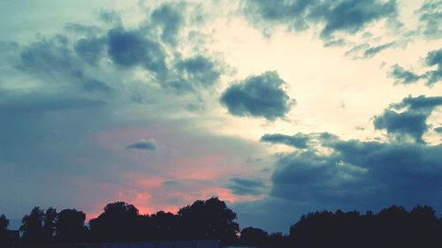 High section of silhouette trees against scenic sky