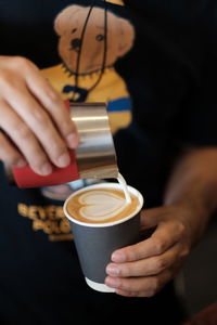 Cropped image of hand holding coffee cup at cafe