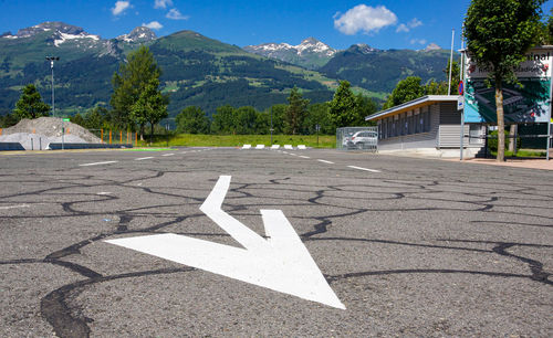 Arrow symbol on road against mountain range