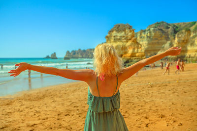 Woman with arms outstretched standing at beach