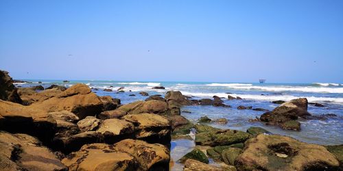 Rocks on beach against clear blue sky