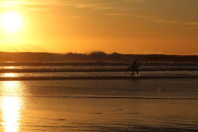 Silhouette surfer walking on the beach