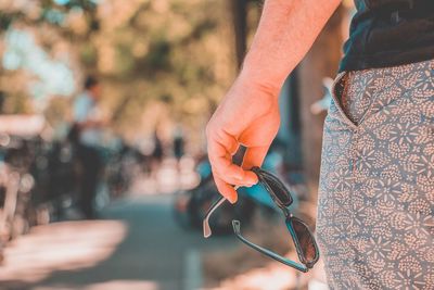 Midsection of man holding sunglasses