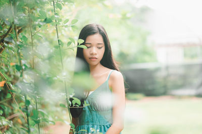 Young woman standing against plants