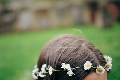 Rear view of girl holding flower on field