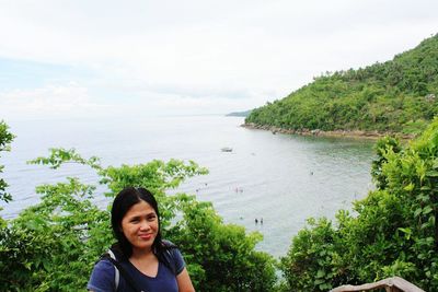 Portrait of smiling woman standing against lake