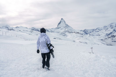 Rear view of man walking on snow covered mountain