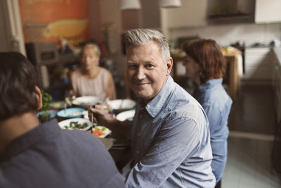 Portrait of happy mature man sitting with friends at table