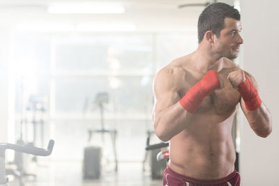 Muscular shirtless man standing in gym