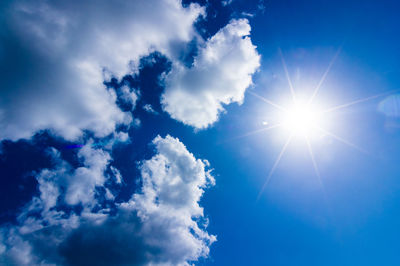 Low angle view of sunlight streaming through clouds