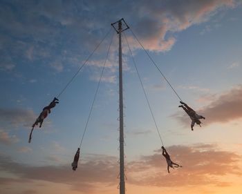 Low angle view of silhouette people enjoying amusement park against sky during sunset