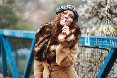 Young woman looking away while standing in snow