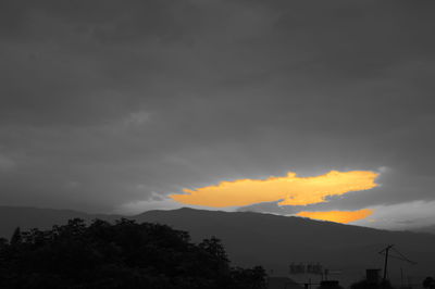 Silhouette of mountain against cloudy sky