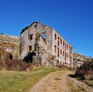 Low angle view of old building against clear blue sky