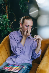 Man applying eyeshadow sitting on chair