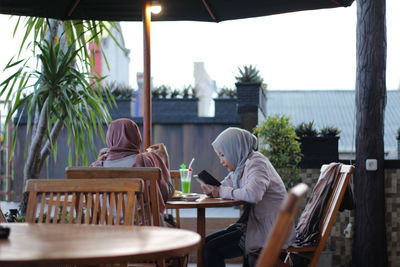 Rear view of man sitting on bench in restaurant