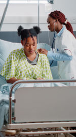 Doctor examining female patient on bed at hospital