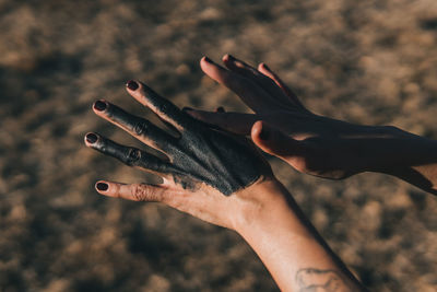 Female hands with dark mud rubbed onto them and black fingernails to show a connection to earth. 