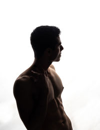 Side view of young man looking away against white background