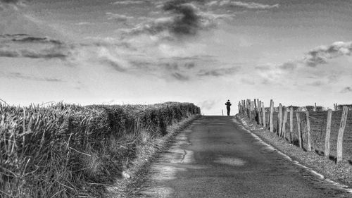 Road amidst field against sky