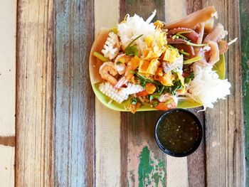 Seafood with dipping sauce served on vintage wooden table.