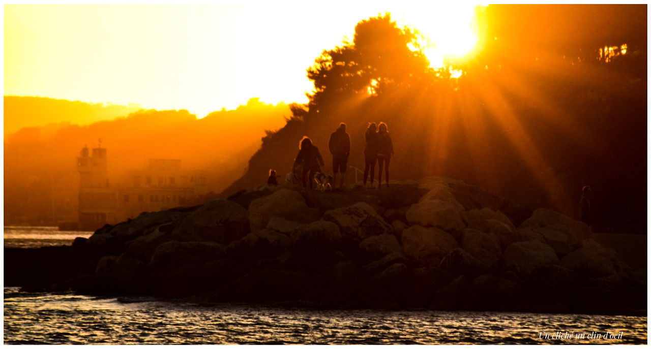 PEOPLE ON SHORE AGAINST SKY DURING SUNSET