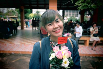 Portrait of smiling mid adult woman with bouquet on street