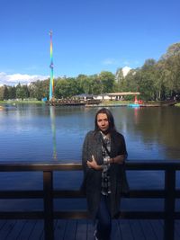 Portrait of woman with arms crossed leaning on railing against lake