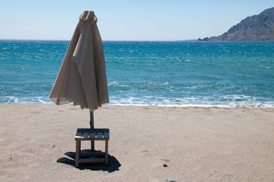 Deck chairs on beach against sky