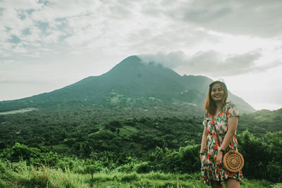 Woman smiling against mountain range and volcano against sky