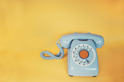 Close-up of telephone booth against yellow wall