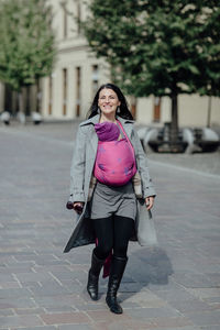 Full length of woman carrying son in scarf on street