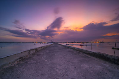 Road by sea against sky during sunset