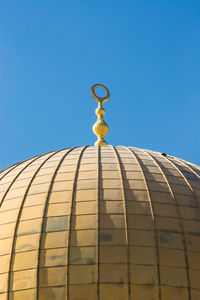 Low angle view of cross against building against clear blue sky