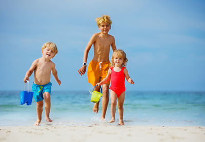 Full length of siblings playing at beach