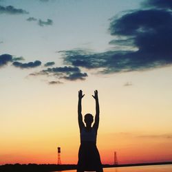 Silhouette woman exercising against sea during sunset