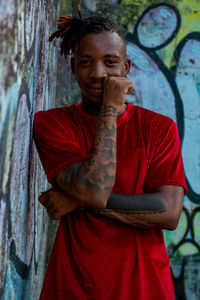 Portrait of young man standing against a graffiti wall