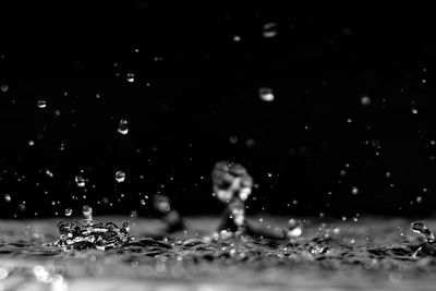 Close-up of water drops splashing on floor against black background