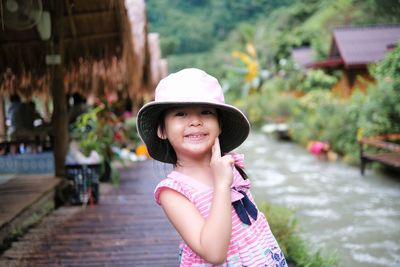 Portrait of young woman standing against river