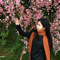 Beautiful young woman touching flowers at park