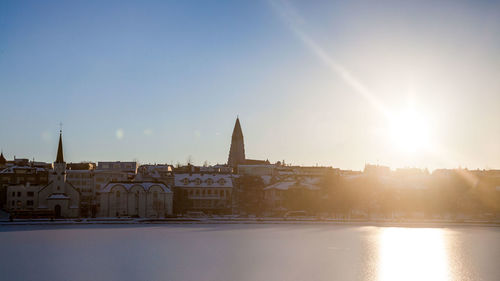 Buildings by river against sky in city