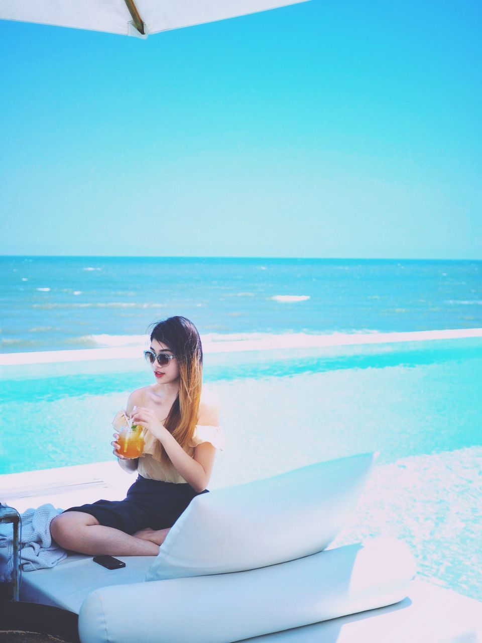 water, sea, food and drink, sitting, horizon over water, leisure activity, horizon, young adult, real people, one person, lifestyles, drink, young women, sky, beach, nature, land, refreshment, glass, drinking, outdoors, beautiful woman