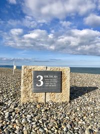 Text on stone wall by sea against sky