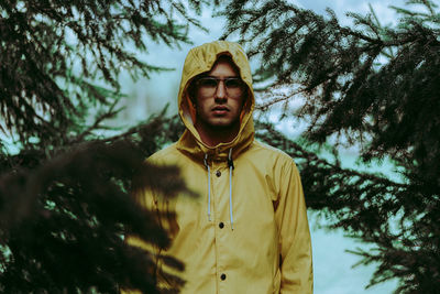 Portrait of young man wearing eyeglasses by pine tree