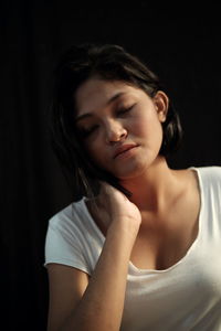 Close-up of young woman against black background