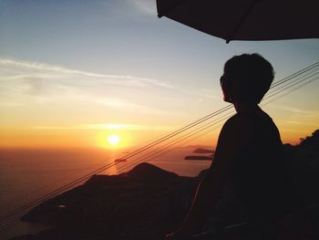 Side view of man looking at sunset