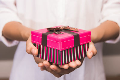 Midsection of woman holding pink gift box