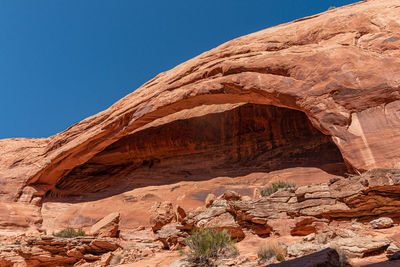 Full frame low angle view of a natural rock arch against a clear blue sky